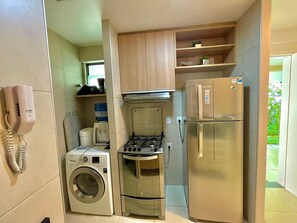 Una cocina compacta con lavadora, estufa y refrigerador.
