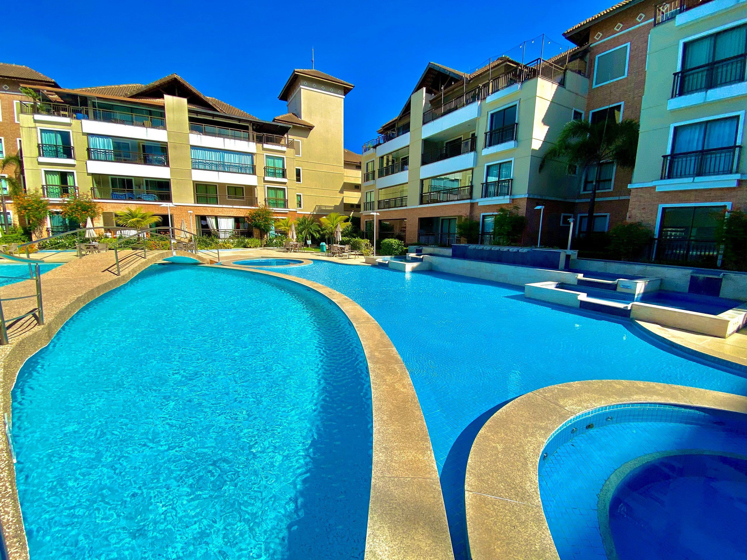 Une grande piscine extérieure entourée d’immeubles à plusieurs étages, dotés de balcons et de fenêtres.