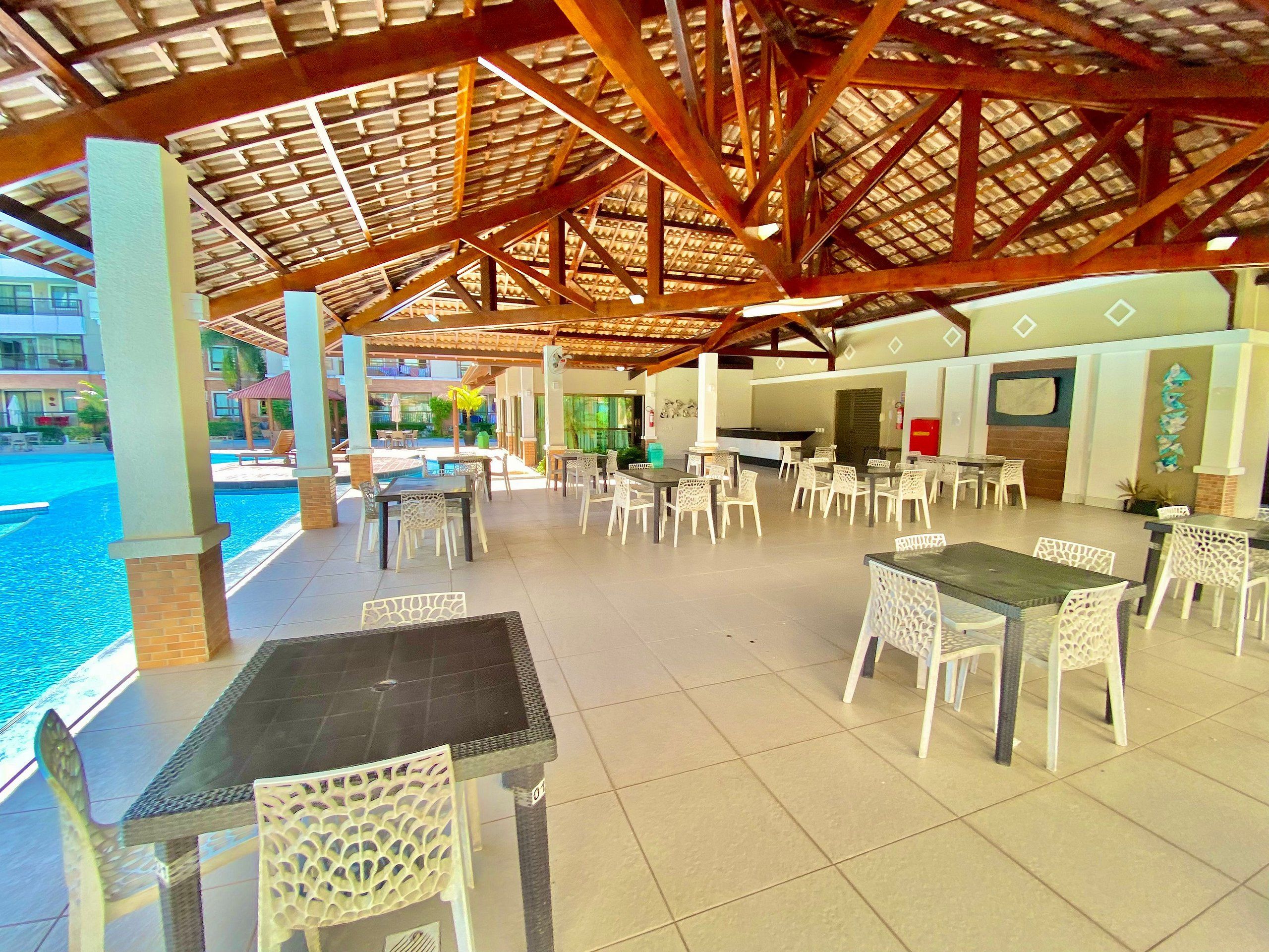 Ein Außenbereich mit Terrassentischen und -stühlen, einem Pool und einer überdachten Lounge-Ecke.