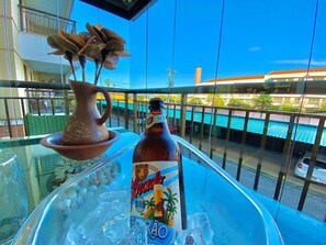 A bottle of beer on a balcony with a clear view of the street and buildings. - Condominio Mediterranee Residence por Be My Guest (Aquiraz)