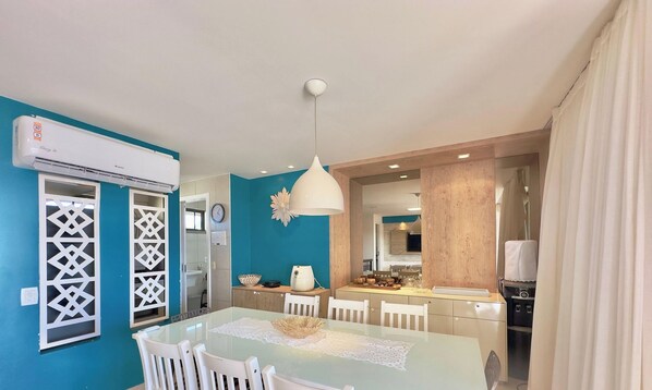 Una cocina moderna con comedor, muebles blancos y una pared azul de acento.