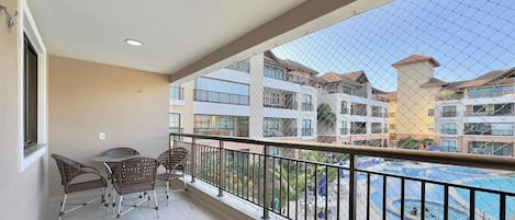 Varanda com vista para uma piscina e edifícios próximos.
