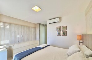 Una habitación de hotel con cama, escritorio, aire acondicionado y ventana.