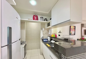 A modern kitchen with a refrigerator, stove, microwave, and a sink. - Condominio Mediterranee Residence por Be My Guest (Aquiraz)
