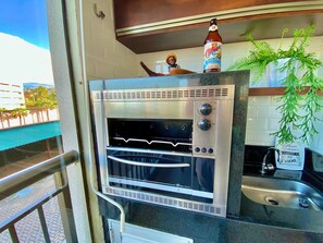 A stainless steel outdoor oven with a digital display, a sink, and a potted plant. - Condominio Mediterranee Residence por Be My Guest (Aquiraz)