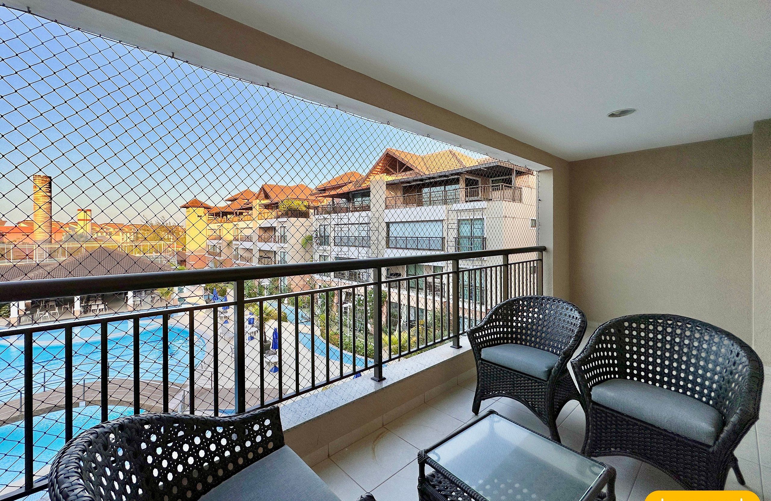 Ein Balkon mit Blick auf einen Pool, Korbmöbel und einem Geländer.