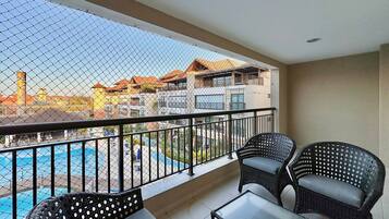 Ein Balkon mit Blick auf einen Pool, Korbmöbel und einem Geländer.