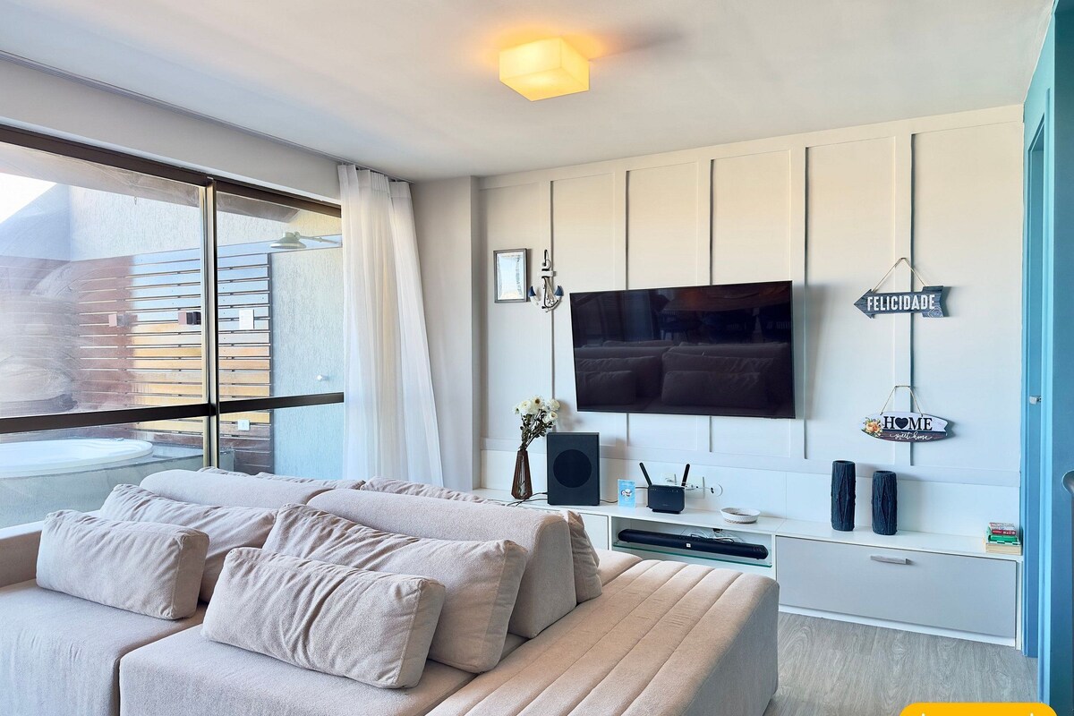 A modern bedroom with a large bed, a TV mounted on the wall, and a balcony with a view.