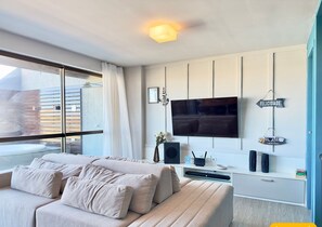 A modern bedroom with a large bed, a TV mounted on the wall, and a balcony with a view. - Condominio Mediterranee Residence por Be My Guest (Aquiraz)