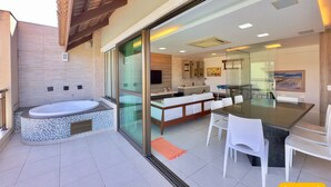 Una cocina moderna con una isla grande, un comedor con mesa y sillas de vidrio, y una zona de hidromasaje separada.