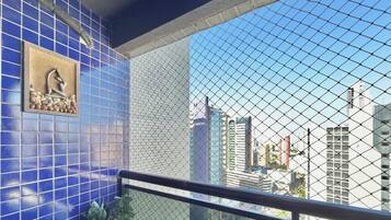 Un balcón con vista a edificios de la ciudad, una pared con azulejos azules y un panel decorativo.