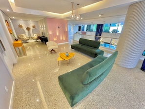 A modern interior with a green sofa, a yellow side table, and a pink accent wall.