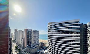 Un edificio alto con fachada curva que da a una playa.