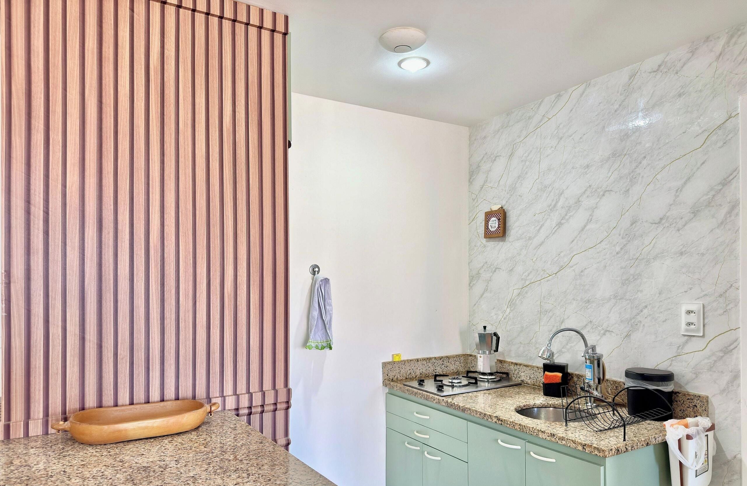 A kitchen with a granite countertop, a sink, a stove, and a wooden cutting board.