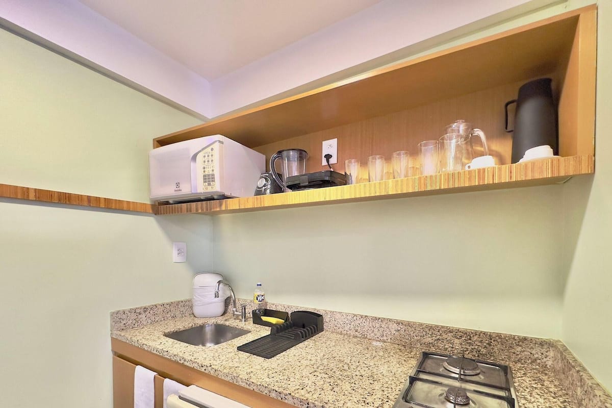 A kitchen with a granite countertop, a sink, a coffee maker, a blender, and a stove.