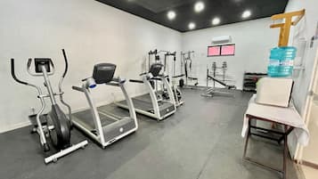 Un gimnasio con cintas de correr, elípticas y equipo de pesas.