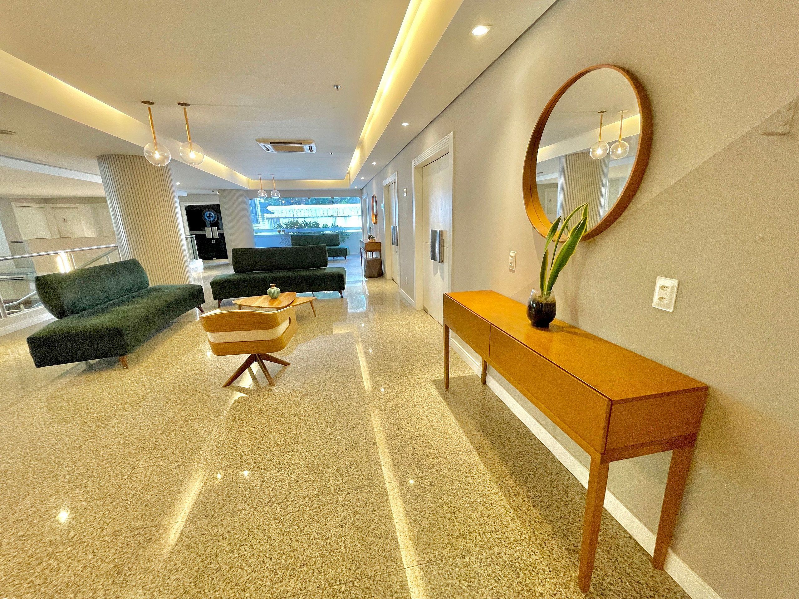 A modern lobby with a sofa, a chair, a console table, and a large mirror.