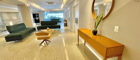 A modern lobby with a sofa, a chair, a console table, and a large mirror.