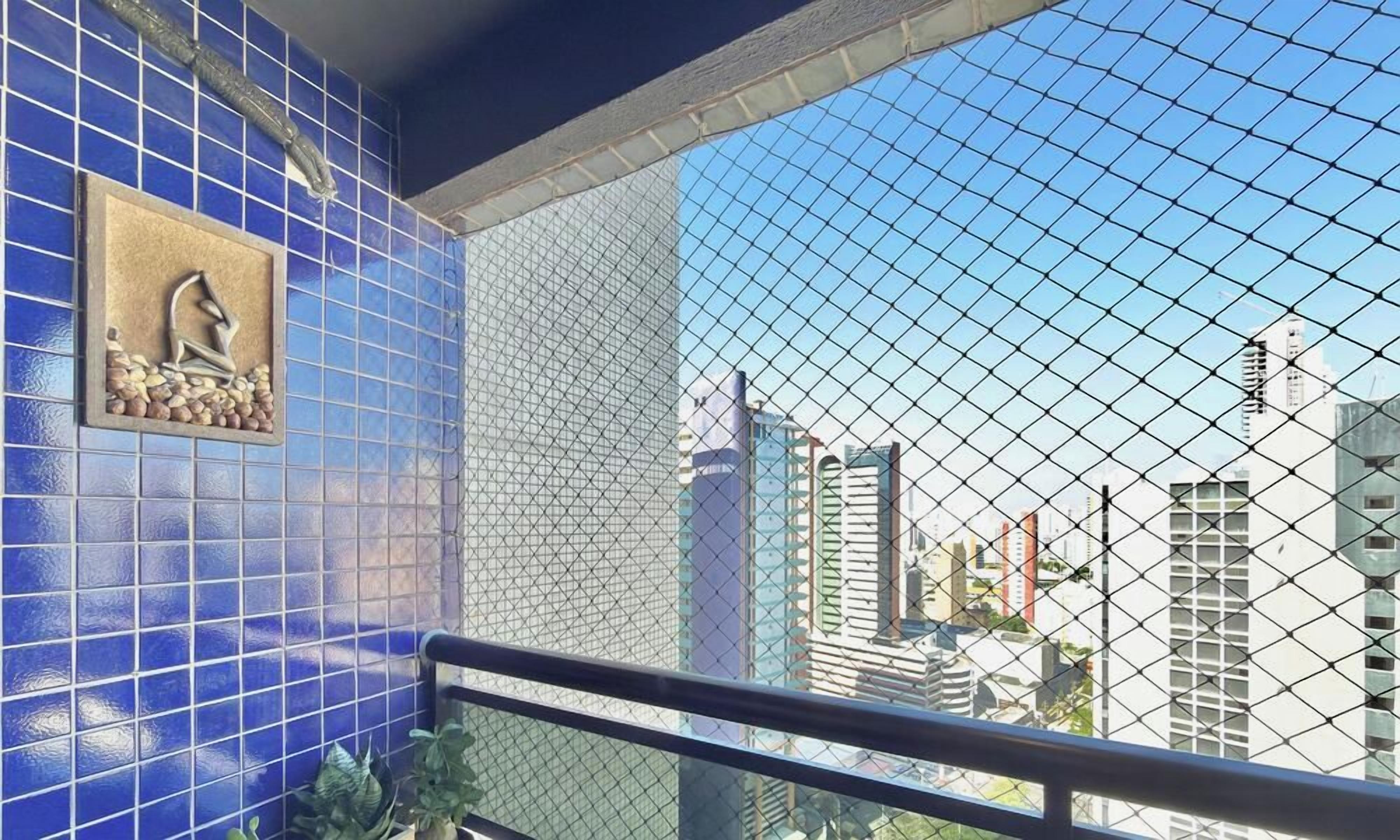 Un balcón con vistas a edificios urbanos, una pared de azulejos azules y un panel decorativo.