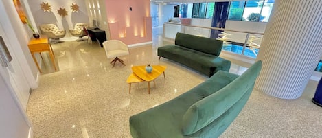 A modern interior with a green sofa, a yellow side table, and a pink accent wall.