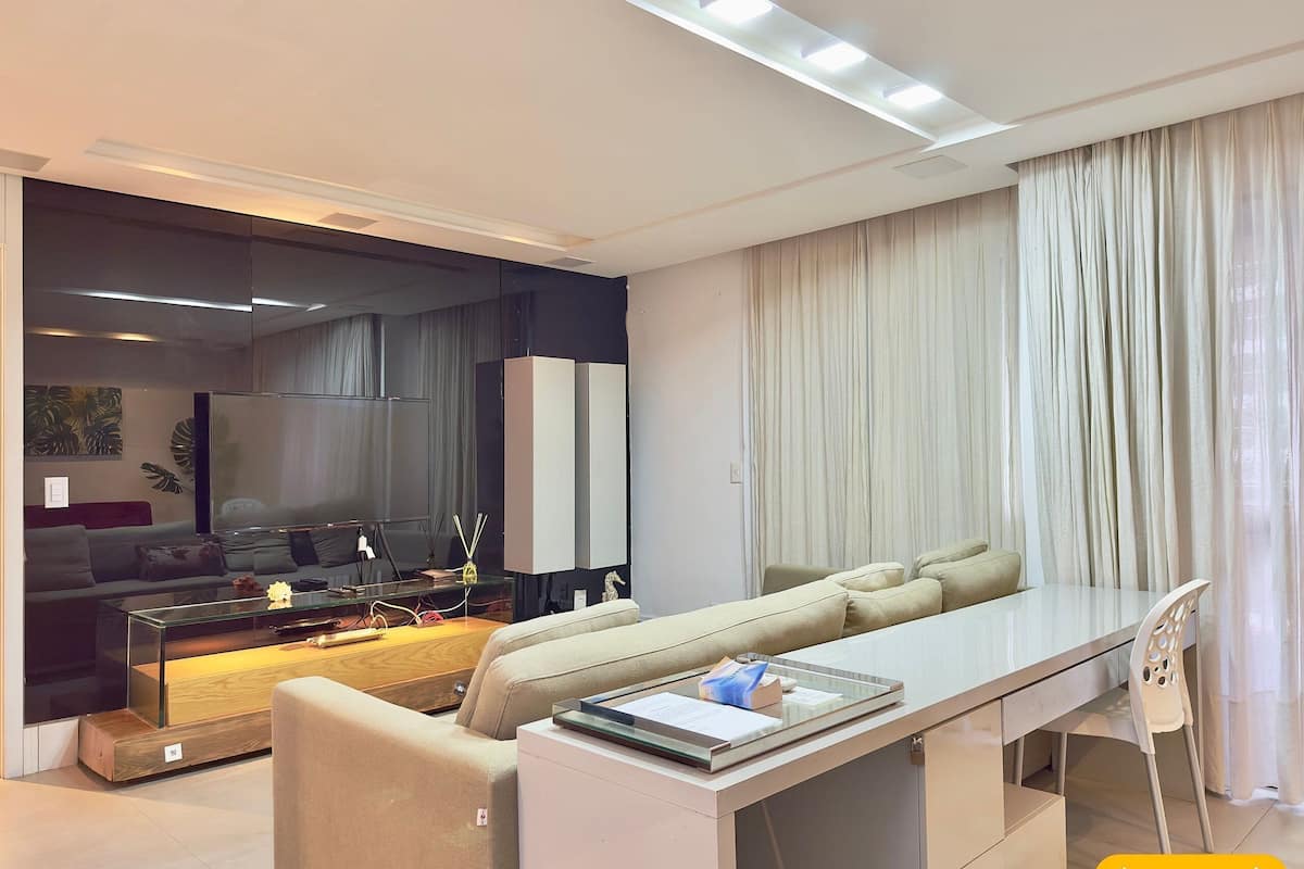A modern living room with a sofa, a glass coffee table, a dining table, and a chair.