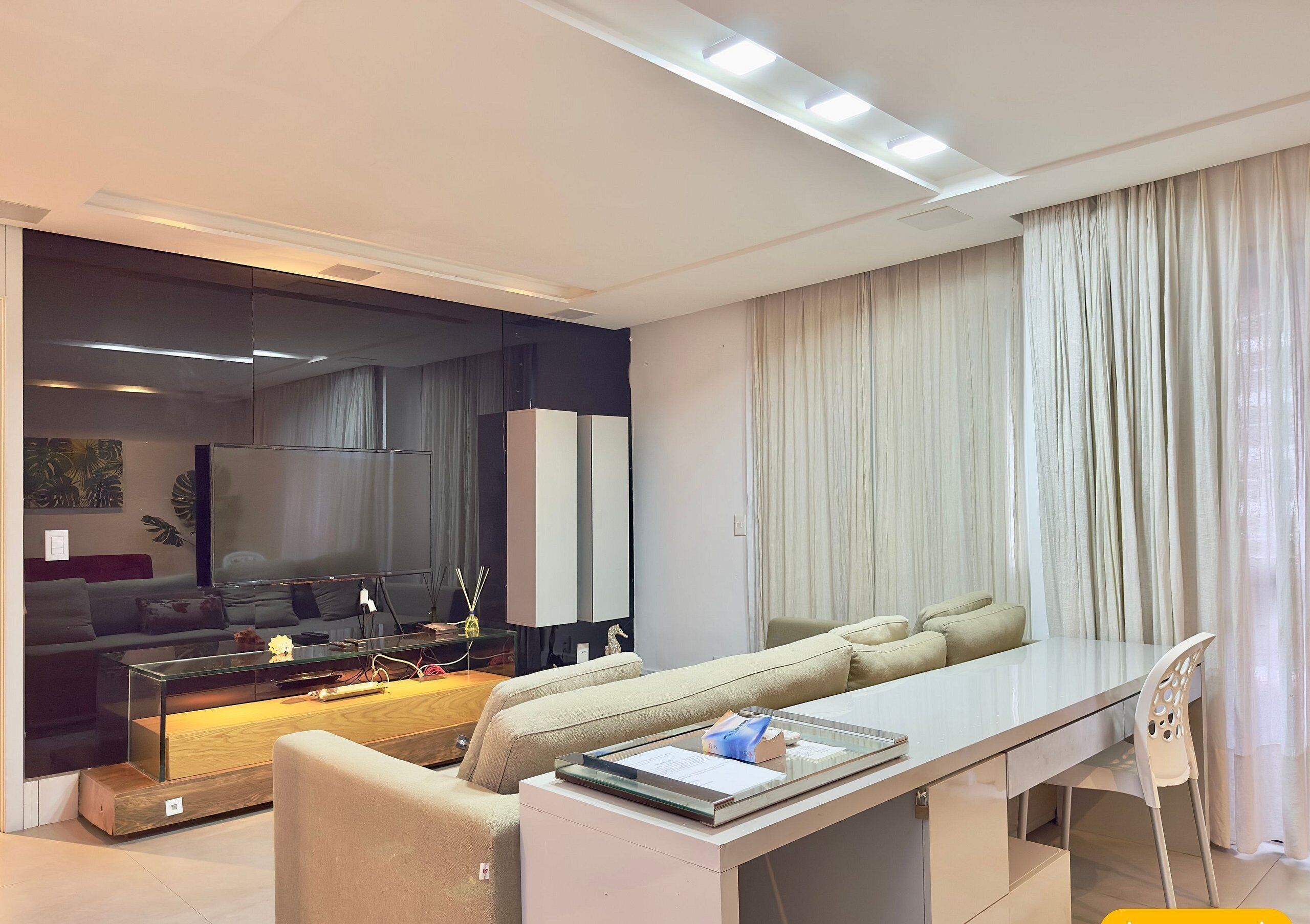 Een moderne woonkamer met een bank, een glazen salontafel, een eettafel en een stoel.