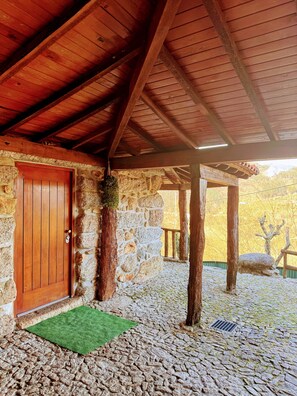 Un edificio de piedra con una puerta de madera, un felpudo verde y una pared de piedra.