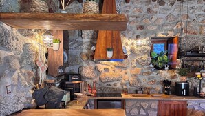 A rustic kitchen with stone walls, wooden beams, and a wine rack.