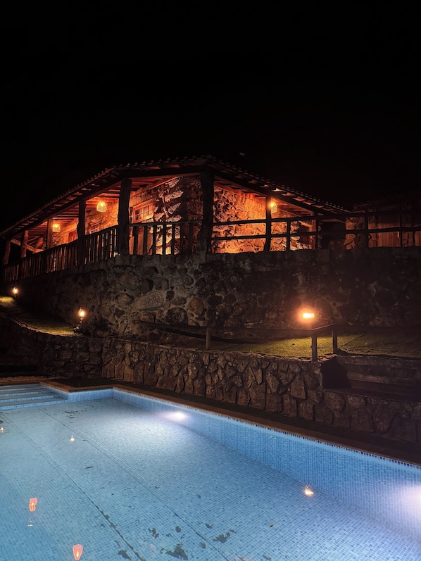Un edificio de piedra con una piscina por la noche.