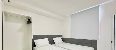 A hotel room with two beds, a wardrobe, and a ceiling light.