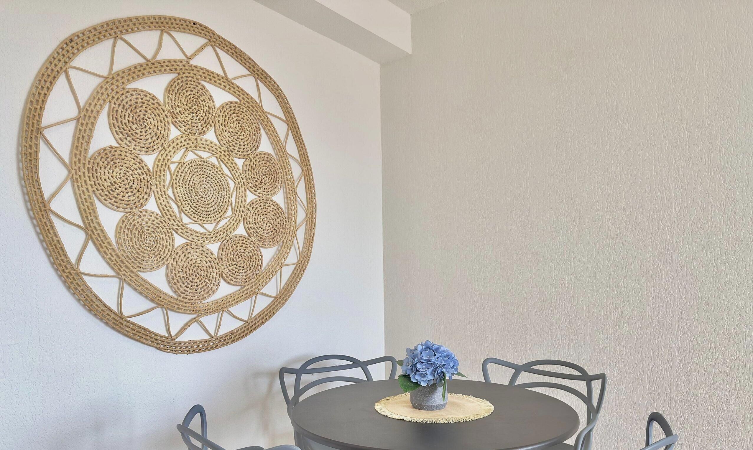 Een eetgedeelte met een ronde tafel, stoelen en een decoratief object aan de muur.