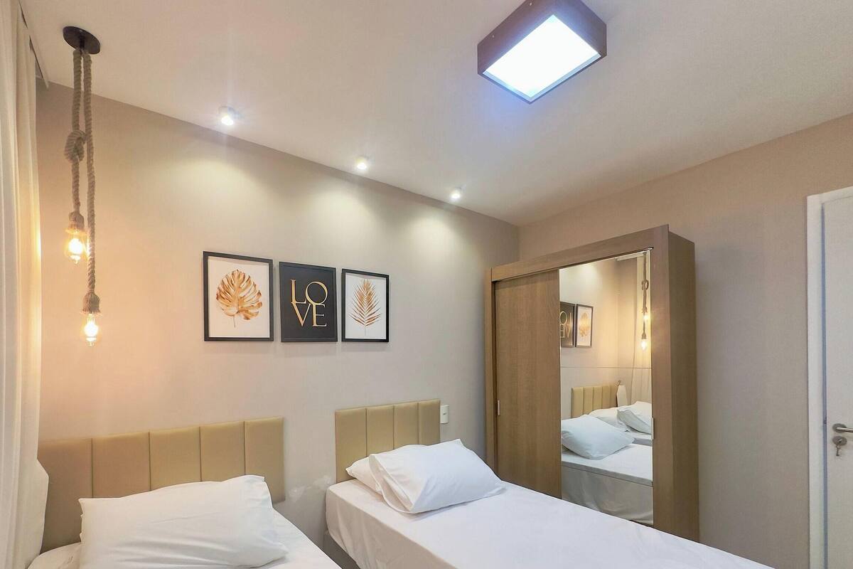 A hotel room with two beds, a mirror, and wall art.