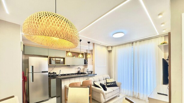 A modern living room with a sofa, a dining table, and a kitchen area with a microwave. - Mirante Condominio Clube (Fortaleza)