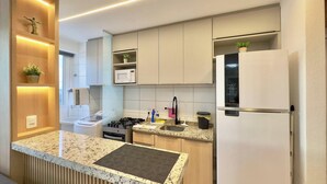 A modern kitchen with a granite countertop, stainless steel appliances, and built-in cabinets. - Mirante Condominio Clube (Fortaleza)