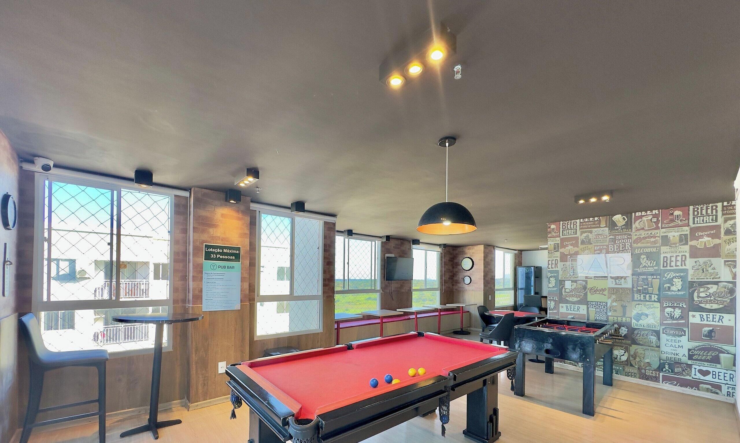 A pool table, foosball table, and a bar area with a view of the outdoors.
