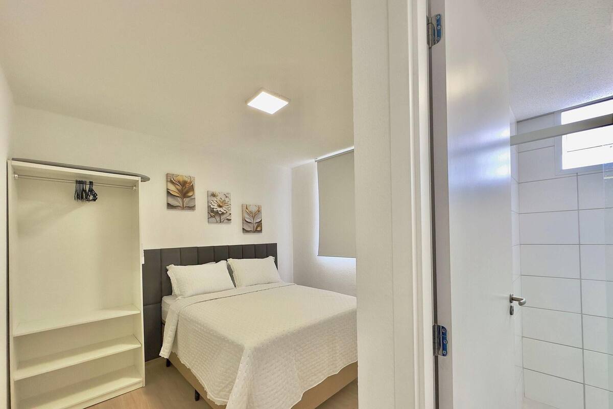 A bedroom with a bed, a wardrobe, a bedside table, and a window.