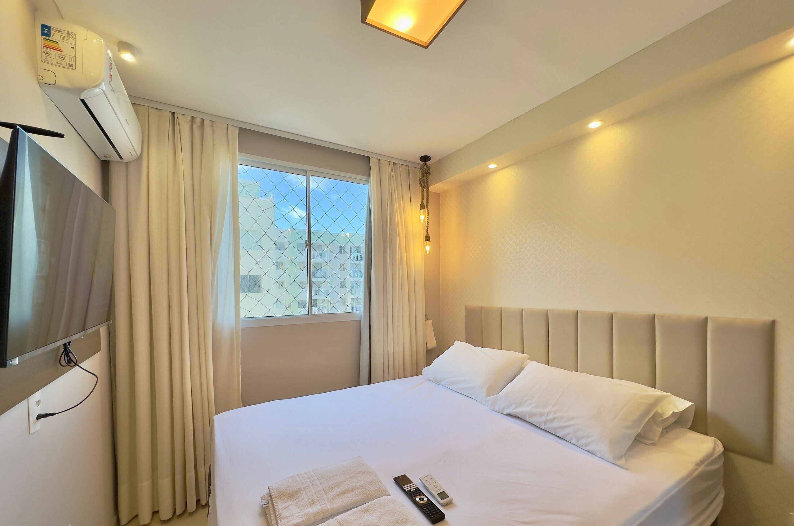Habitación de hotel con cama, televisión, aire acondicionado y ventana con cortinas.