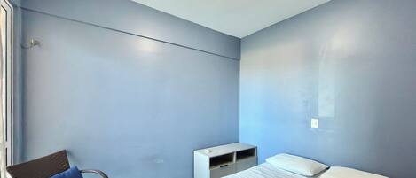 Una habitación con una cama, una silla, un escritorio pequeño y una lámpara.