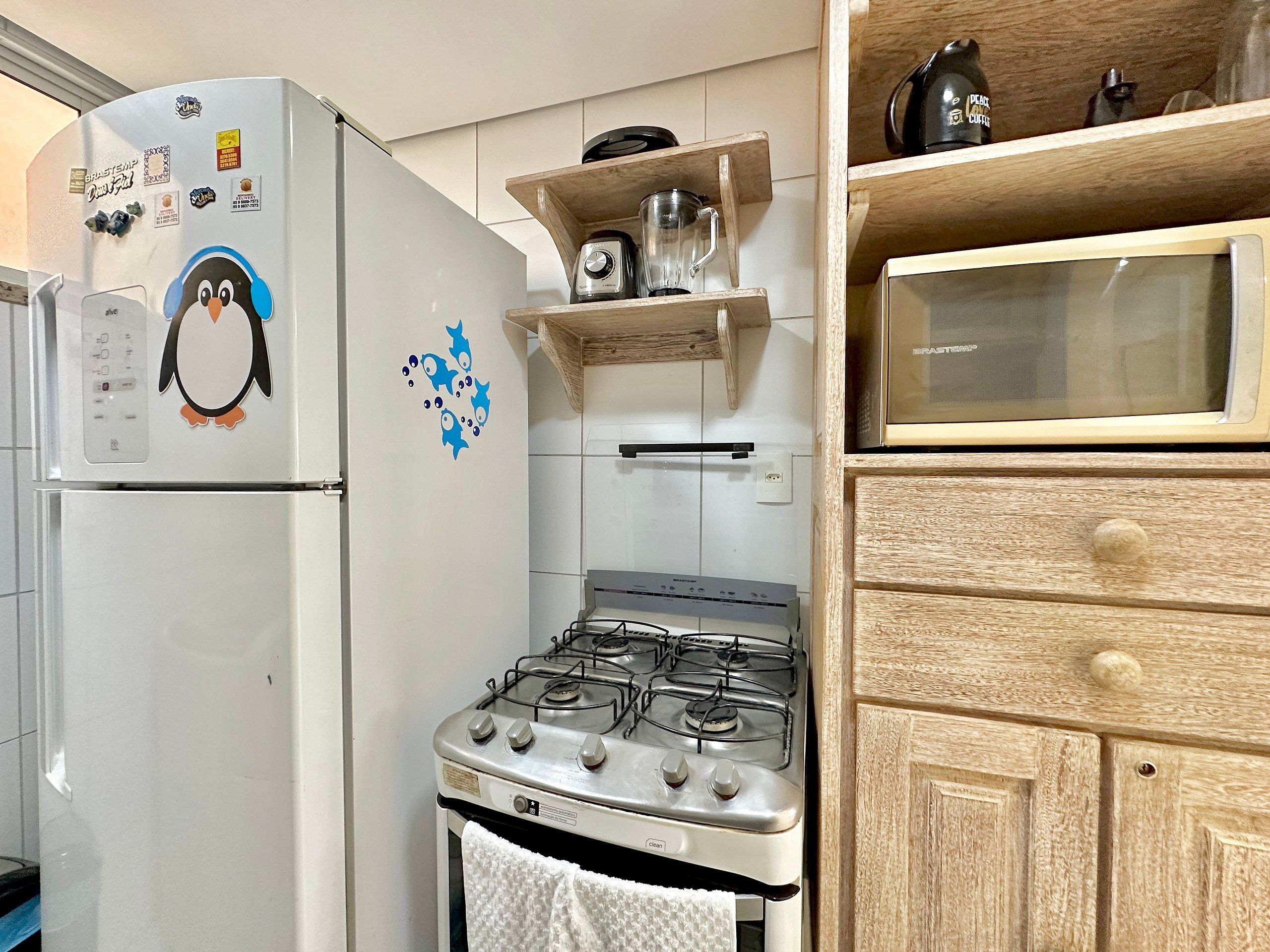 A kitchen with a white refrigerator, a stove, and wooden cabinets.