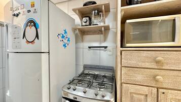 A kitchen with a white refrigerator, a stove, and wooden cabinets.