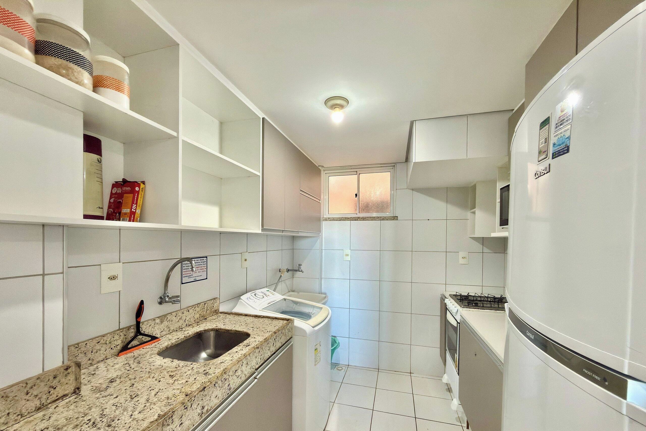 A compact kitchen with white cabinets, a granite countertop, a stainless steel sink, and a built-in oven.