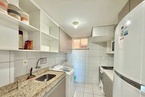 A compact kitchen with white cabinets, a granite countertop, a stainless steel sink, and a built-in oven. - Palm Beach Porto das Dunas - CE (Aquiraz)