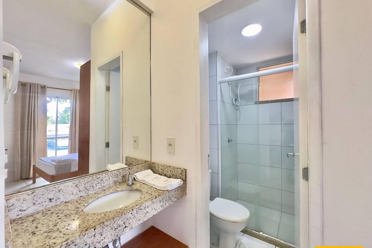 A bathroom with a granite countertop sink, a toilet, and a glass shower enclosure.