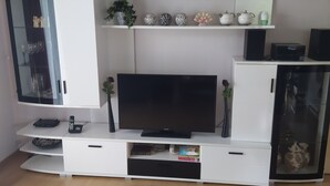 Ein modernes Wohnzimmer mit Flachbildfernseher, weißen Schränken, Dekoration und einer Vitrine.