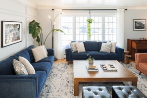 A living room with two blue sofas, a wooden coffee table, and a hanging plant. - Lewis Point Charlottetown Retreat (Charlottetown)