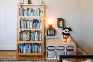 Une pièce avec une bibliothèque, un doudou à l’effigie de Mickey Mouse et une petite table dotée de bacs de rangement.