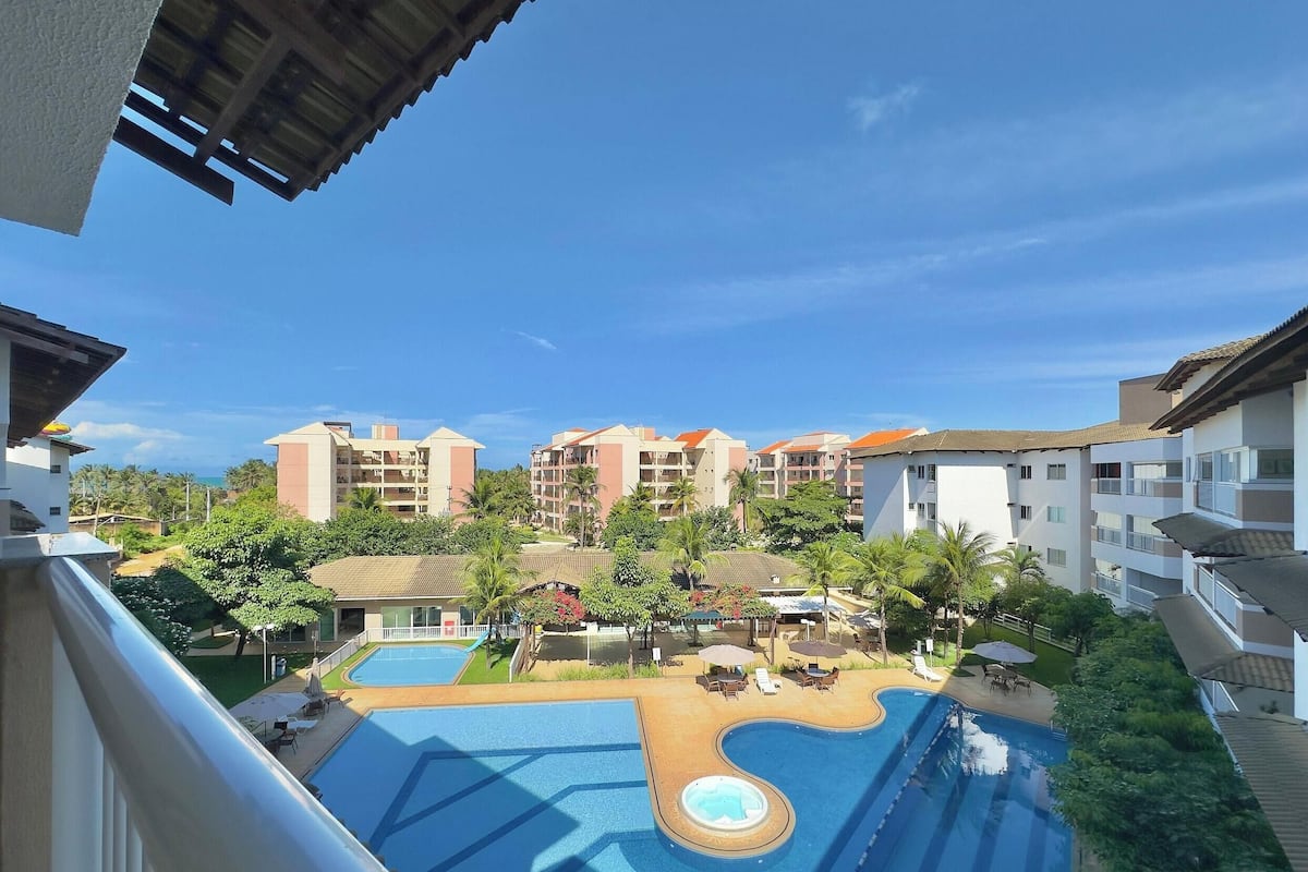 A hotel with a swimming pool, outdoor seating, and multiple buildings with balconies.