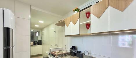 Una cocina moderna con armarios blancos, encimera de granito, un lavabo y una estufa.