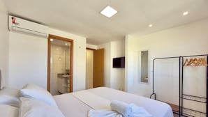 Hotellihuone, jossa on kaksi sänkyä, vaatekaappi, televisio ja ilmastointilaite.