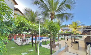 A courtyard with a pool, palm trees, and outdoor seating. - Porto Beach Residence (Aquiraz)